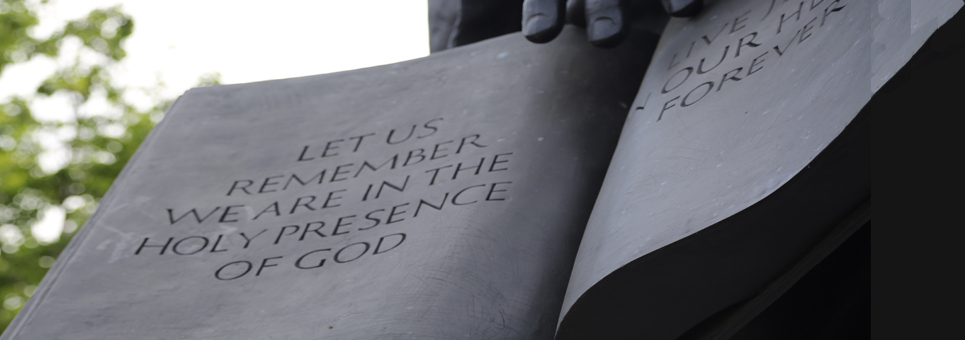 Statue of book pages, 'let us remember we are in the holy presence of God'