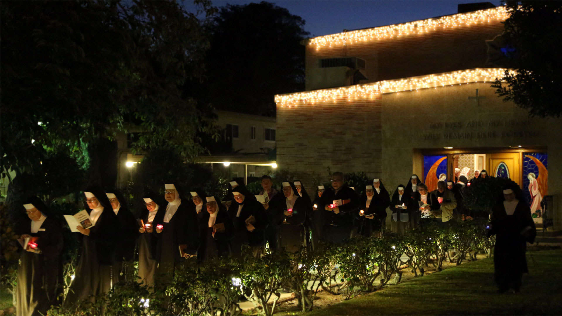Community holding candles and walking out of Chapel at night