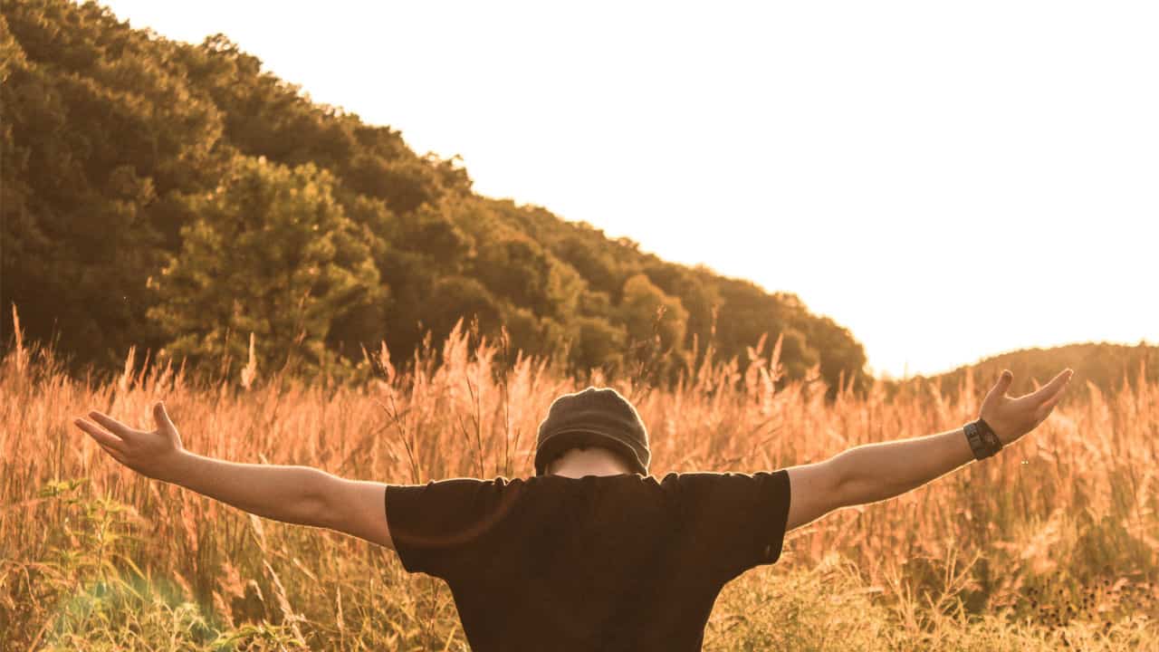 man with arms spread out in nature