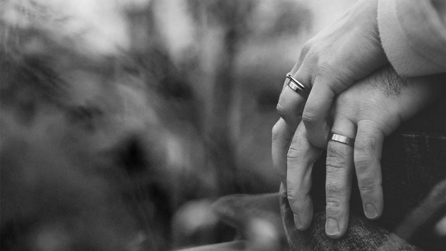 black and white photo of hands holding showing wedding rings