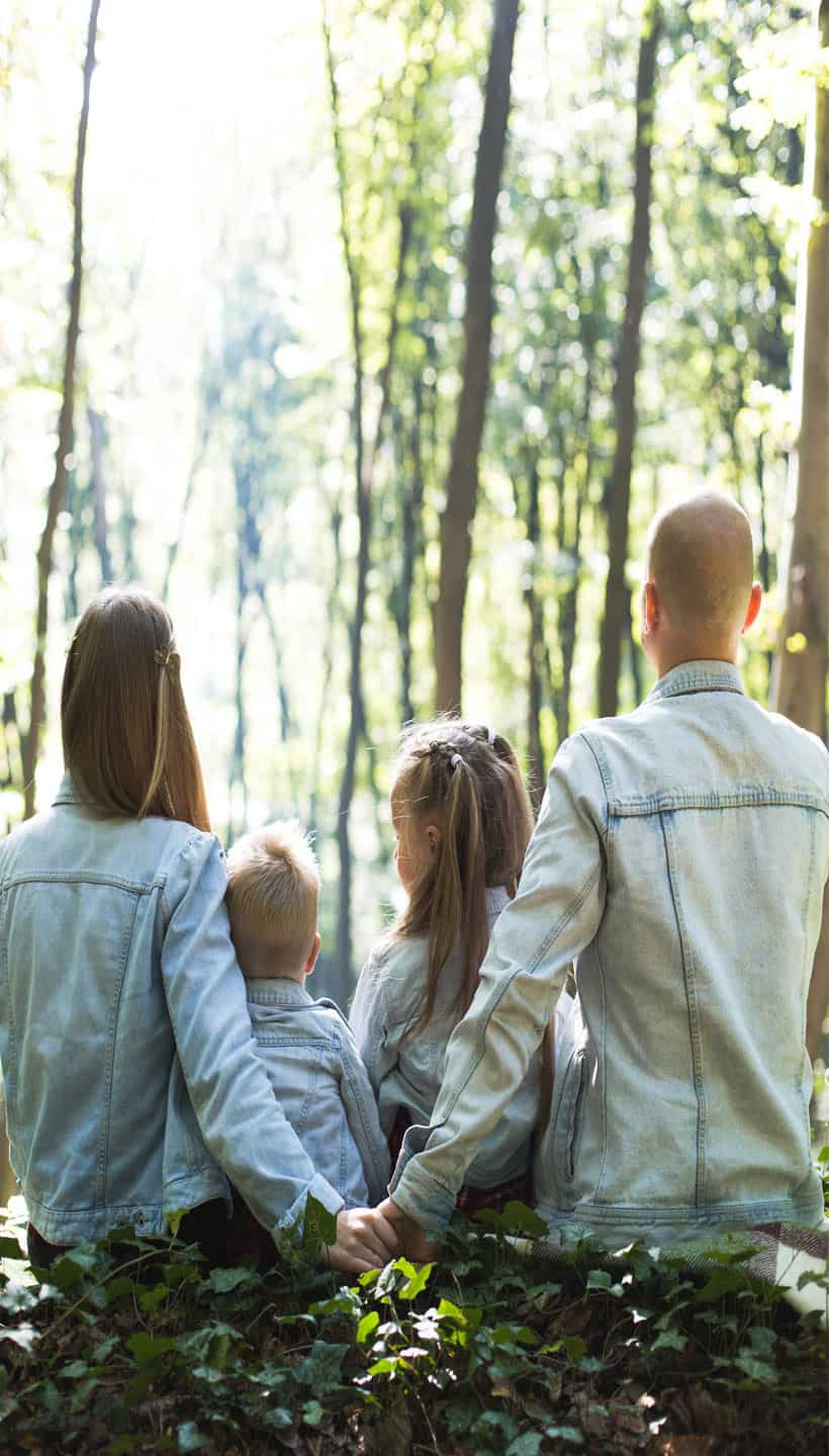 family and two kids sitting in the forrest