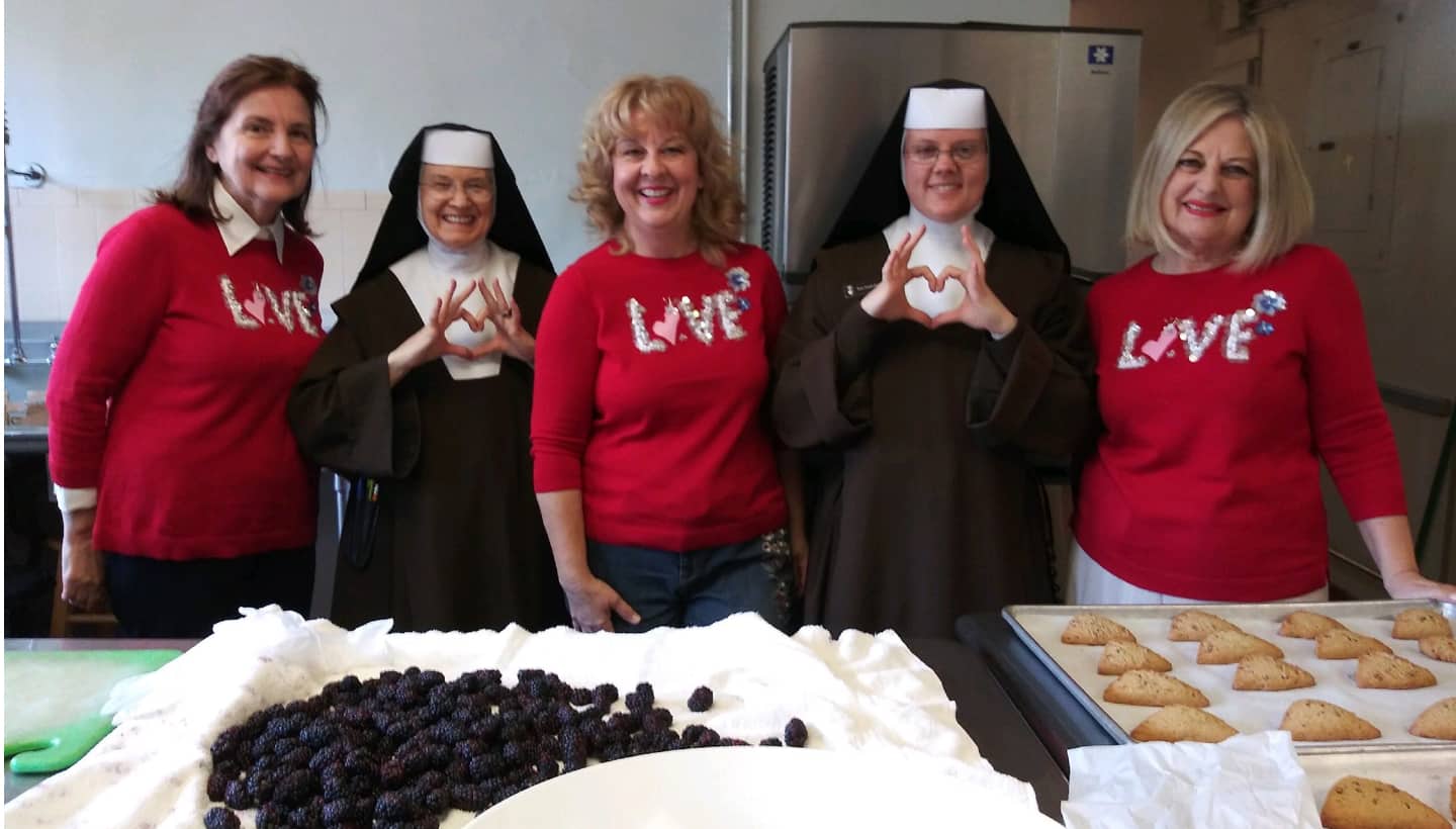 Sisters and Volunteers in kitchen, hands making hearts