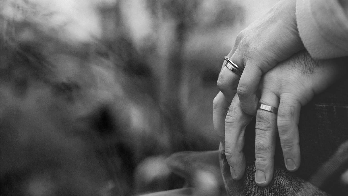 black and white image, hands holding showing wedding rings