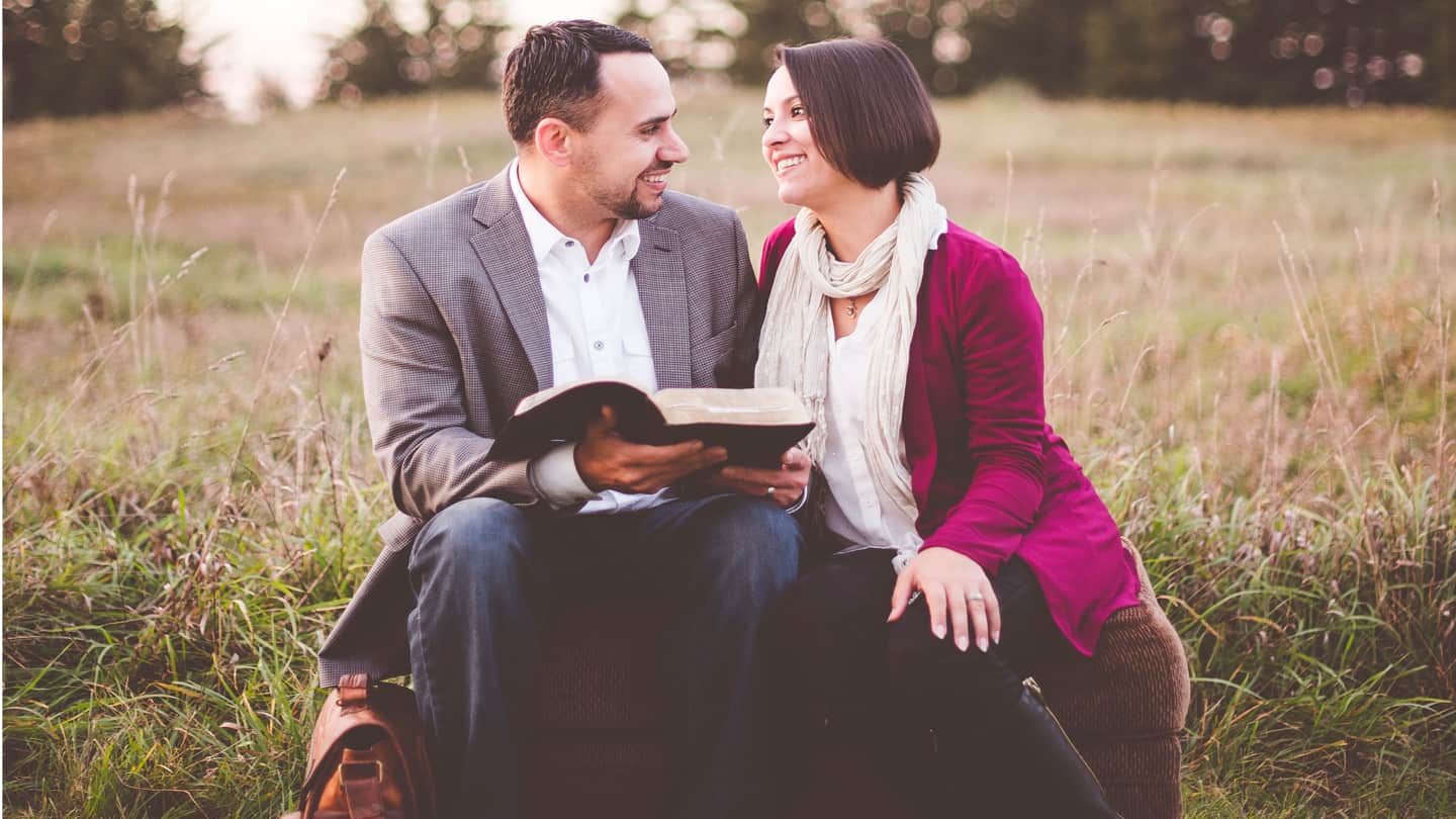 Couple reading bible in the middle of a field