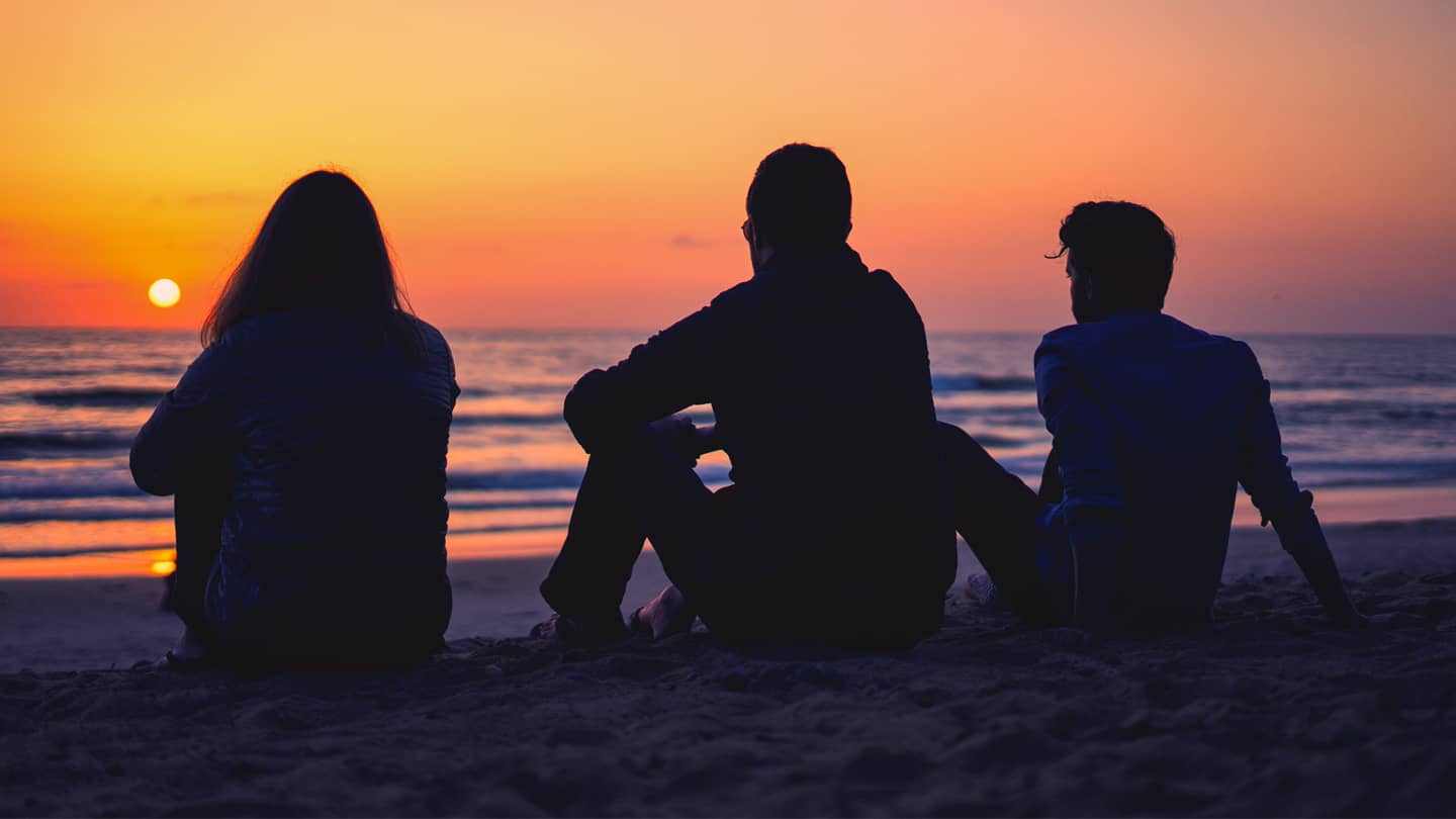 TrueFreedom_1440 silhouette of people sitting on beach watching the sunset