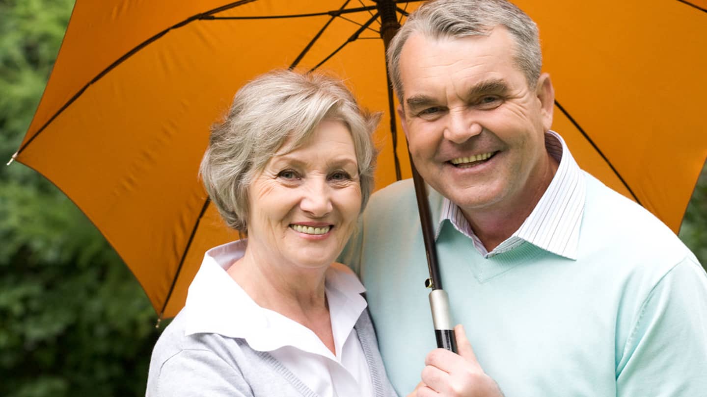 Senior_smile_1440 Caucasian couple smiling, holding umbrella