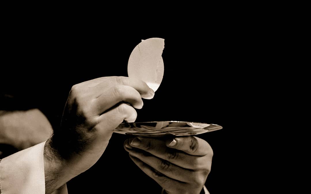 close up of priest holding eucharist during consecration