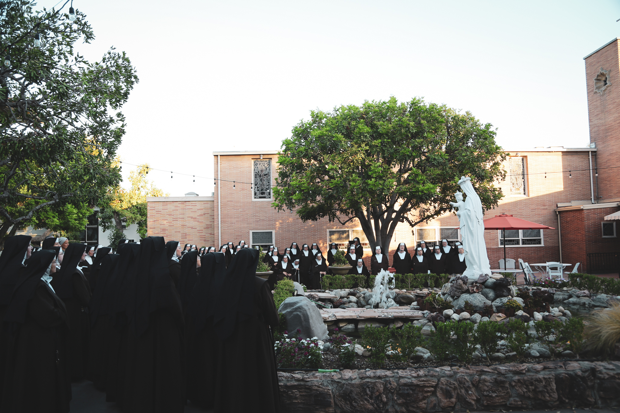 Community of Sisters standing around fountain and Mary statue