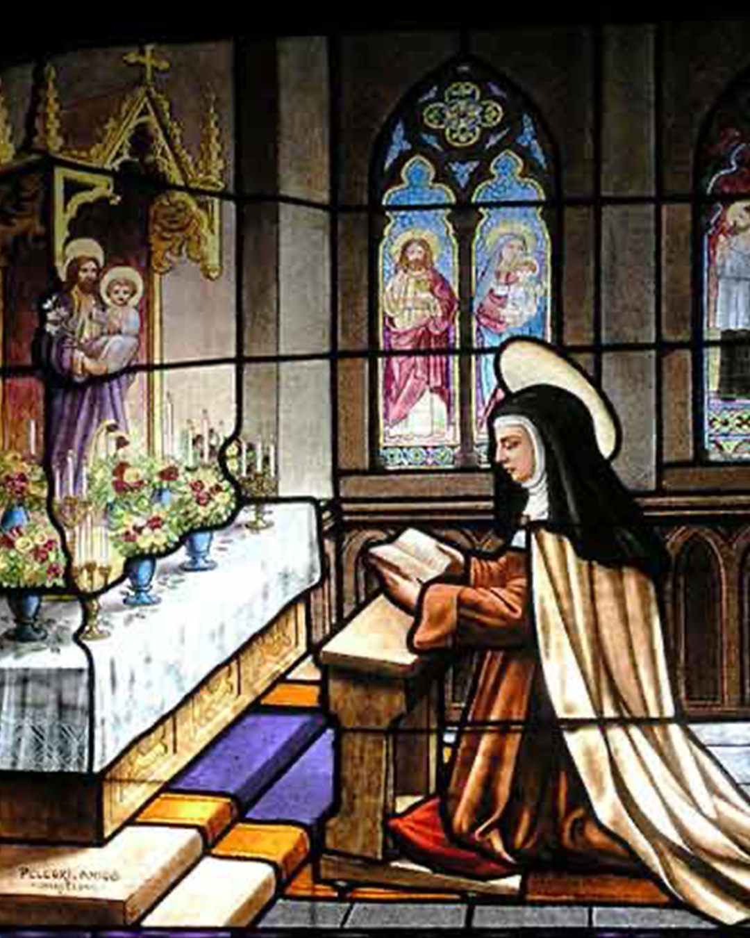 Stained glass of St. Teresa of Avila kneeling in a chapel before a statue of Jesus.