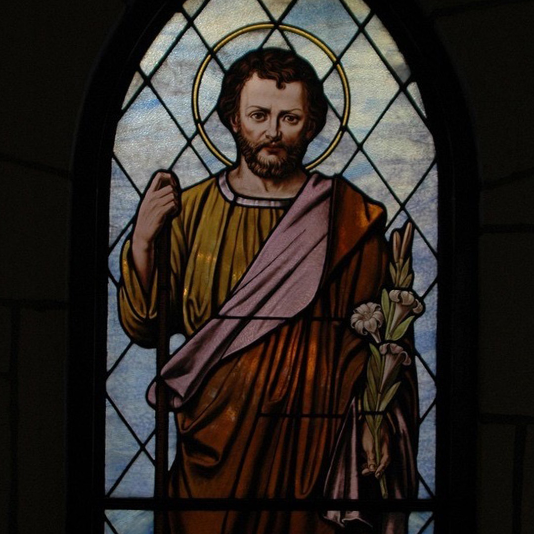 Stained glass of St. Joseph holding staff and flowers.