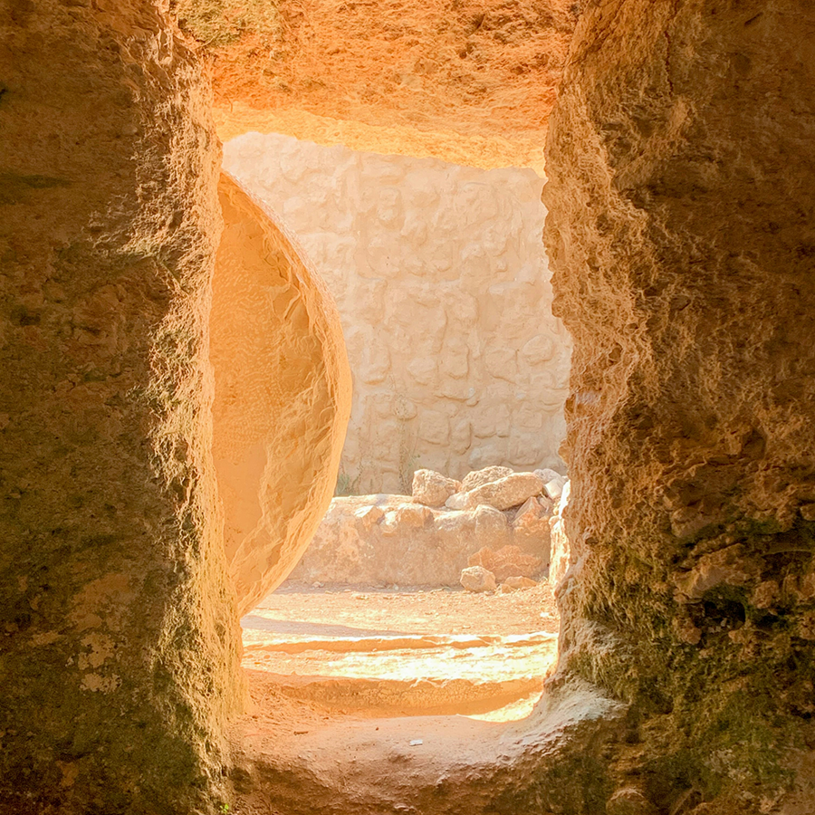 View from within a stone cave, a large circular stone door has been rolled to the side.