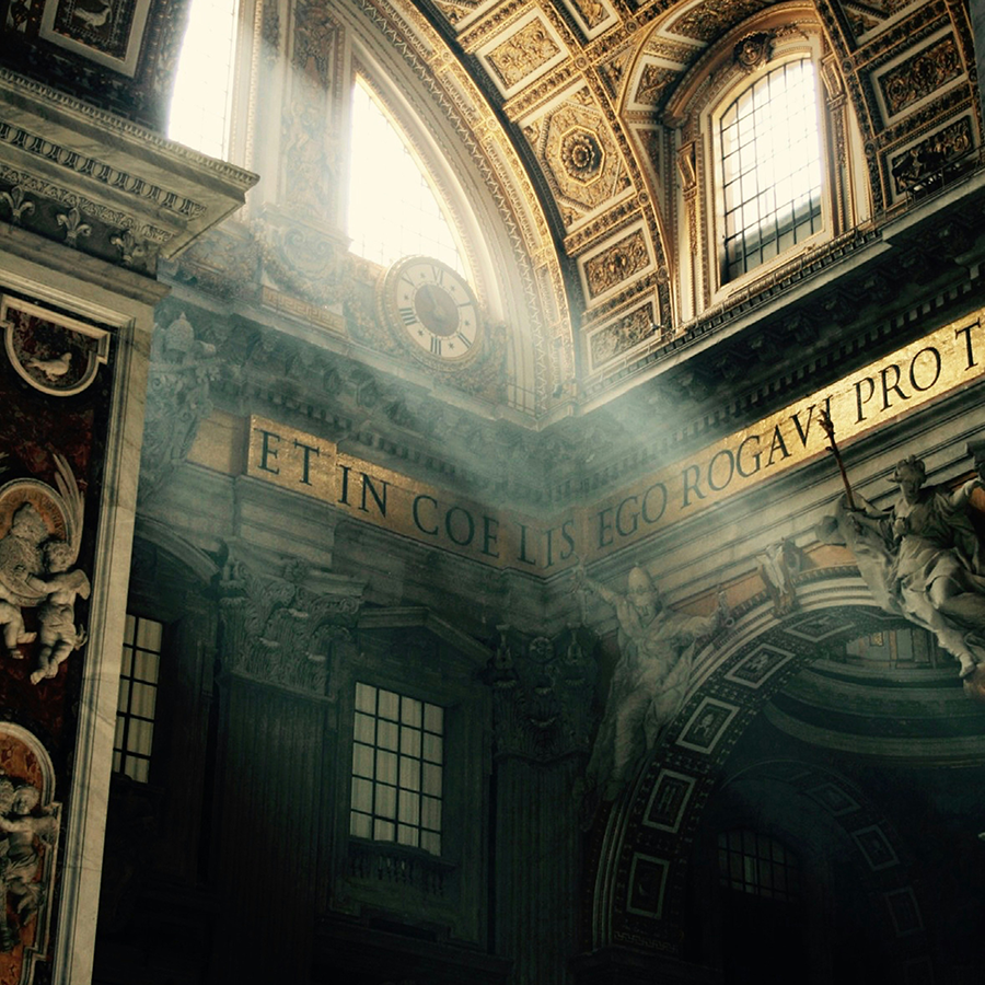 Beams of light stream into a chapel with an ornate ceiling and murals.