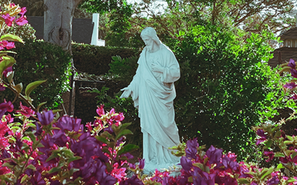 White statue of Jesus framed by flowers in the garden of Sacred Heart Retreat House.
