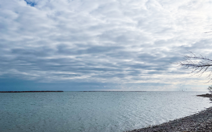 A cloudy sky over a still ocean. The blue of the sky almost merges with the sea.