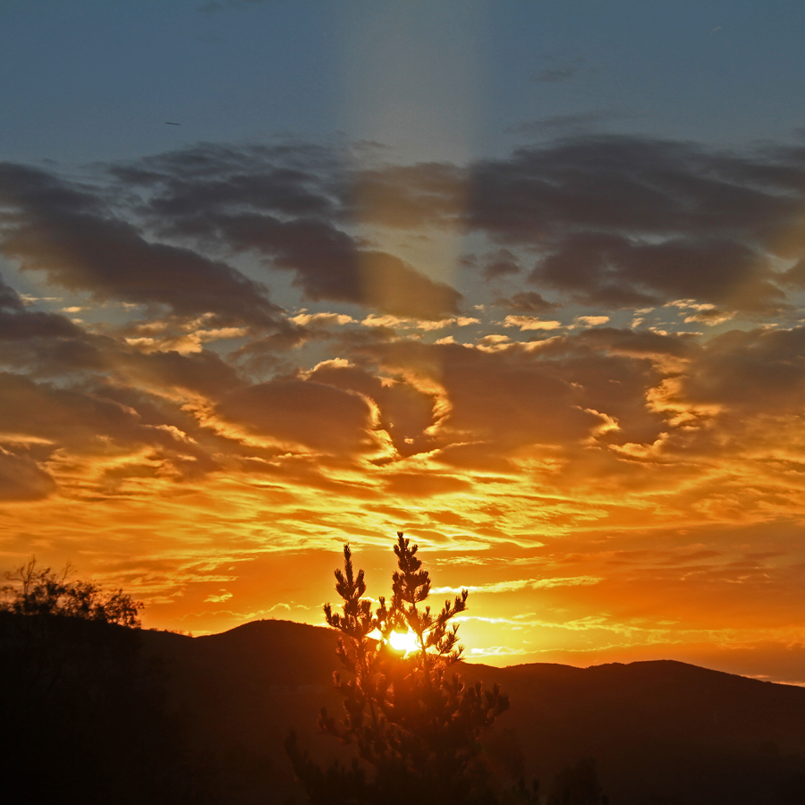 Sunrise over a mountain horizon. The sky is bathed in orange light.
