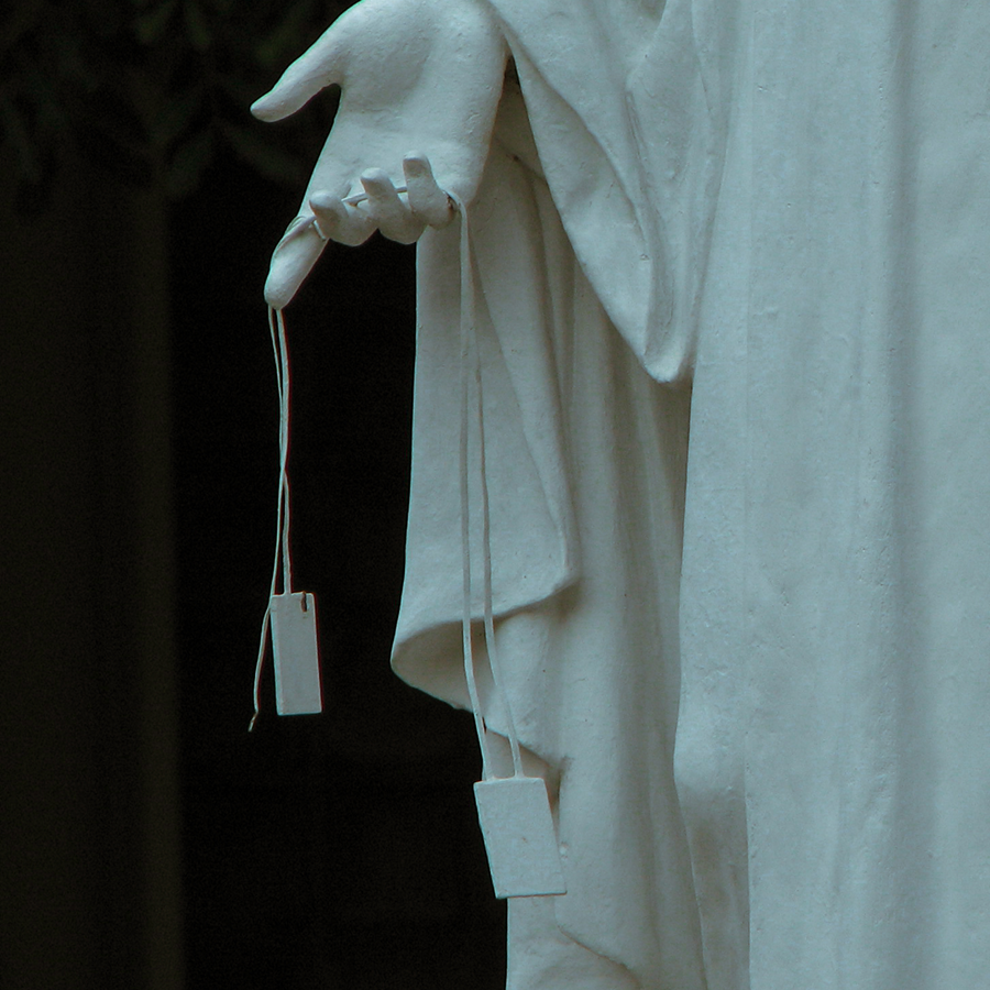 The hand of a statue of Mary. A scapular hangs from her fingers.