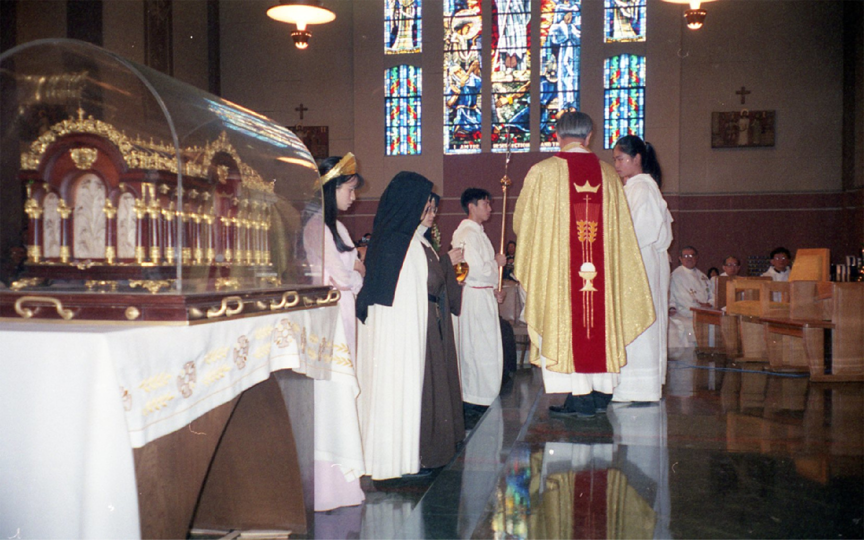 Two sisters bringing up the offertory gifts during mass. The relics of St. Therese sit a few feet away in the center of the church.
