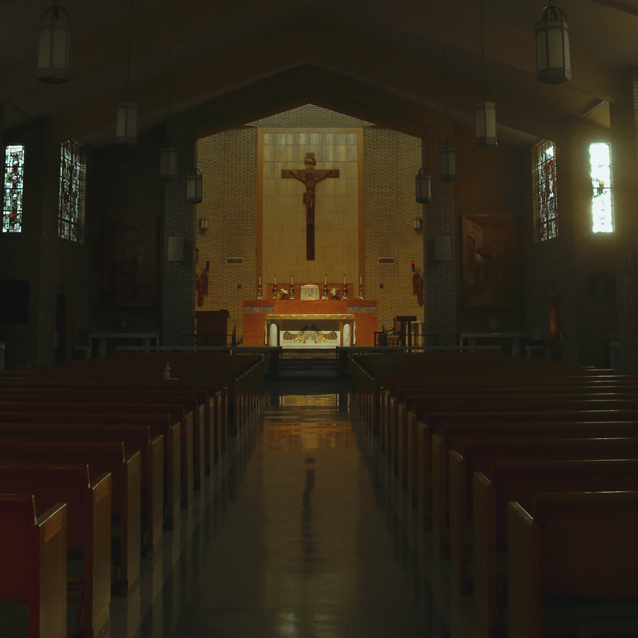Crucifix behind the altar in an unlit chapel.