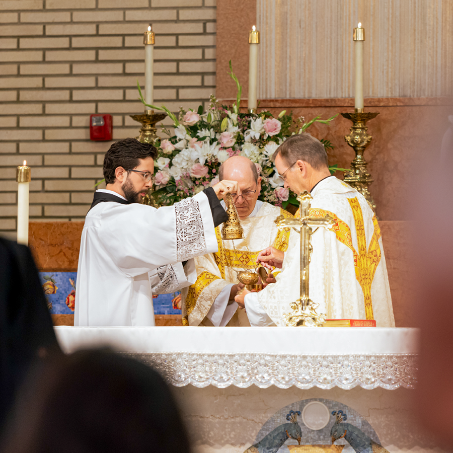 Two priests and a seminarian performing the Consecration on the Eucharist.