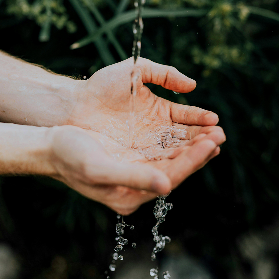 Water streaming into cupped hands.